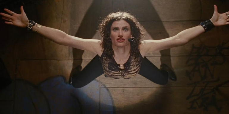 Maureen standing in the spotlight with her arms out