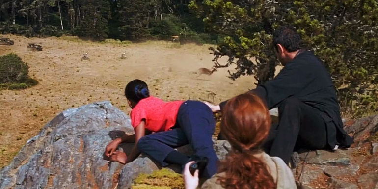 Kelly Malcolm Looking at Dinosaurs while leaning over a rock in The Lost World