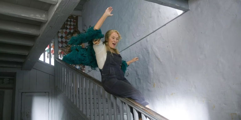 Donna sliding down the stair rail 