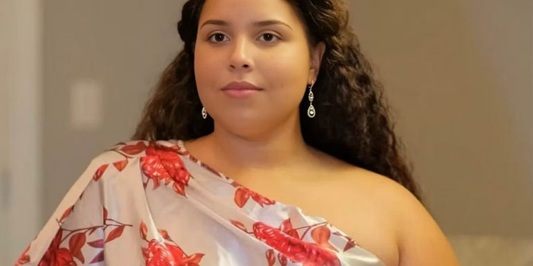 Winter Everett The Family Chantel wearing a print dress smiling slightly