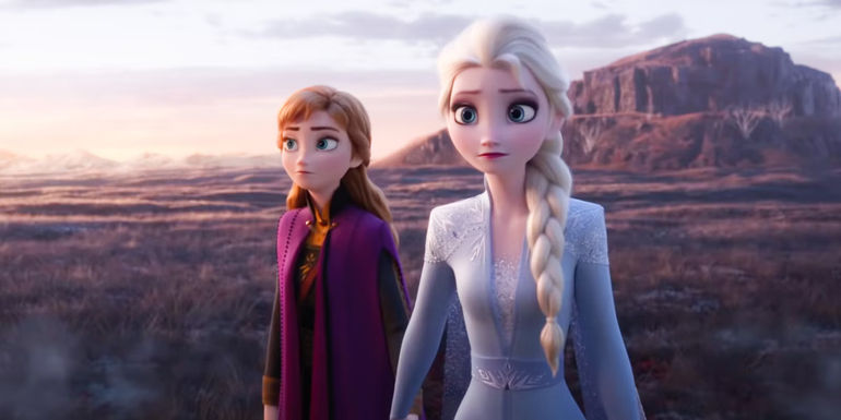 Anna and Elsa standing together looking serious in front of mountainous background in Frozen II