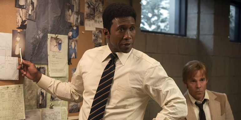 Mahershala Ali pointing to a photo on a board in a scene from True Detective season 3.