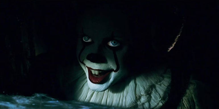 Bill Skarsgård's Pennywise smiling in the shadows of the drain in It 2017