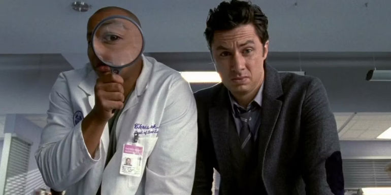 Turk looking through a magnifying glass while stood next to J.D in Scrubs