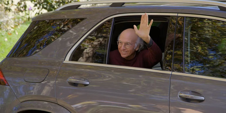 Larry waves from a car window in Curb Your Enthusiasm