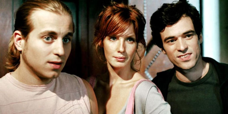 Kelly Reilly standing in between two men and looking sideways in Russian Dolls