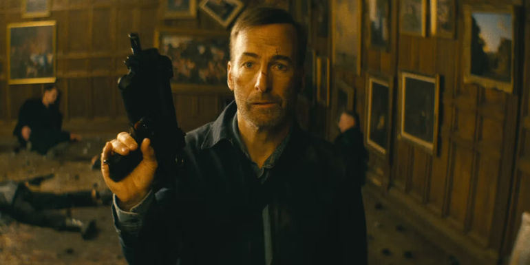 Bob Odenkirk as Hutch Mansell holds a submachine gun in Nobody.