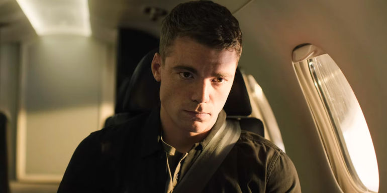 Peter Sutherland sitting in a window seat on a jet in The Night Agent.