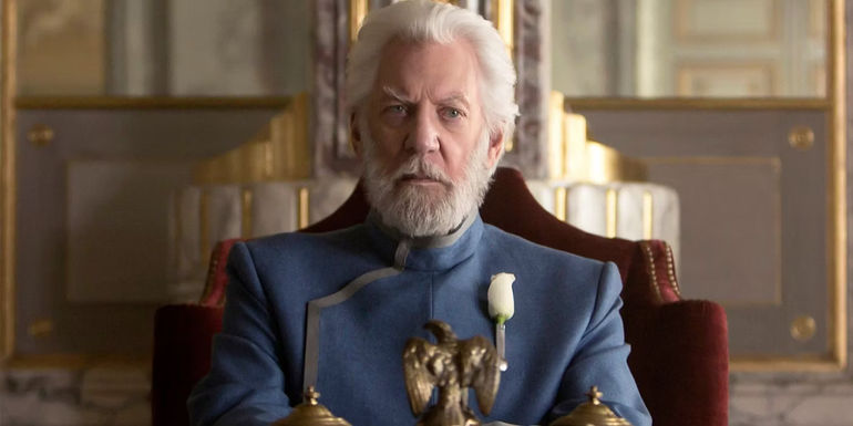 Donald Sutherland as President Snow sitting at a table in The Hunger Games