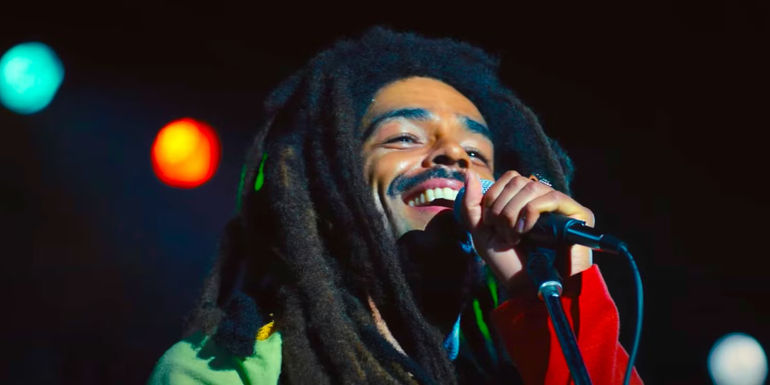 Kingsley Ben-Adir as Bob Marley smiling while singing in Bob Marley: One Love