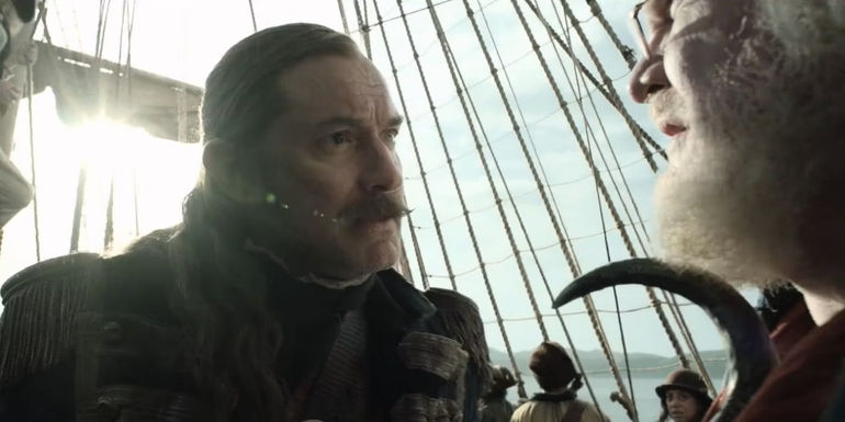 Captain Hook (Jude Law) pointing at Smee (Jim Gaffigan) with his hook in Peter Pan & Wendy.