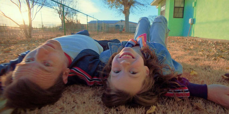 Devyn McDowell and Ewan McGregor on the ground as she smiles into the camera in Bleeding Love