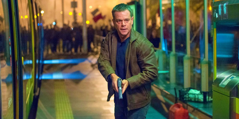 Matt Damon as Jason Bourne holding a gun