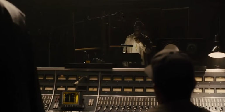 Tupac (Marcc Rose) looking out from the recording booth in Straight Outta Compton.