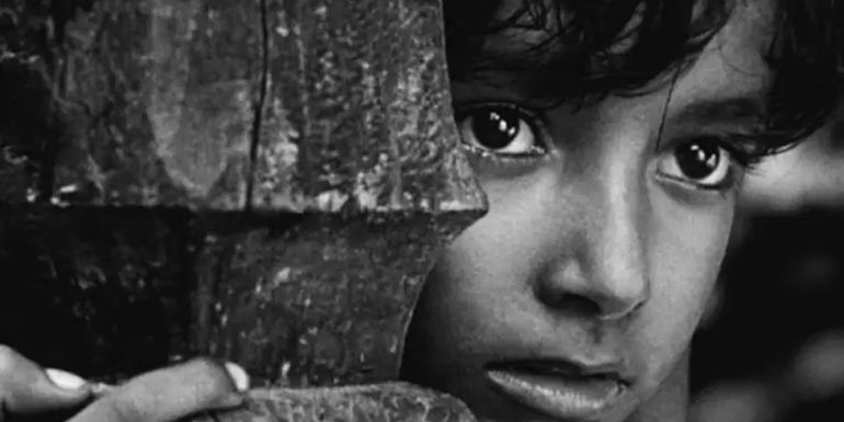 Subir Banerjee as Apu hides behind a column while spying in Pather Panchali