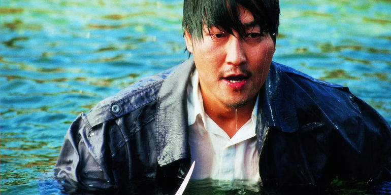 Song Kang-ho as Park Dong-jin wades throug the water with a knife in Sympathy For Mr. Vengeance