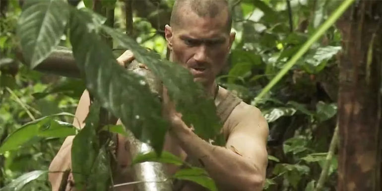 Shane Lewis on Naked and Afraid carrying a large stick through the jungle