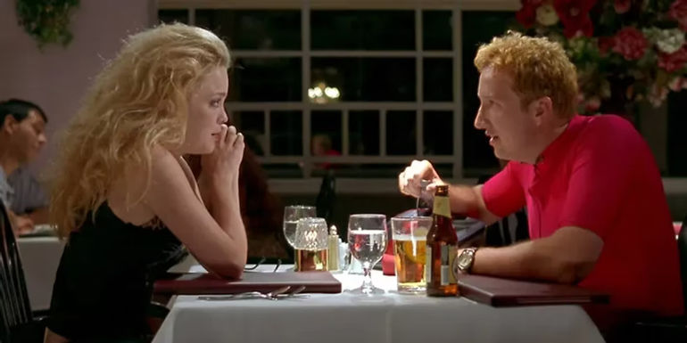 Ursula (Marisa Coughlan) dressed as a biker chick and Foster (Paul Soter) dressed as a bicyclist talking to each other over dinner in Super Troopers.