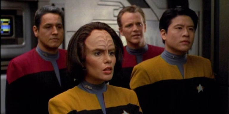 Chakotay, Tom Paris, B'Elanna Torres, and Harry Kim stand together in the USS Voyager's corridor in Star Trek: Voyager.