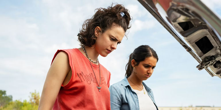 Drive-Away Dolls Jamie and Marian looking down at a car