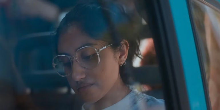 Emma writing on a postcard and looking out of the window of the van. 