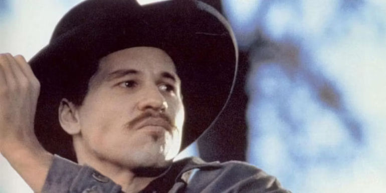 Doc Holliday (Val Kilmer) looks at something on his side in Tombstone.