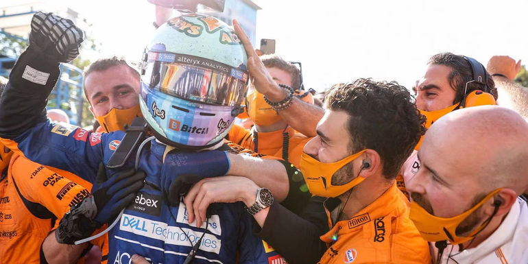 formula 1 - drive to survive celebration shot with team patting driver on head while he wears a helmet