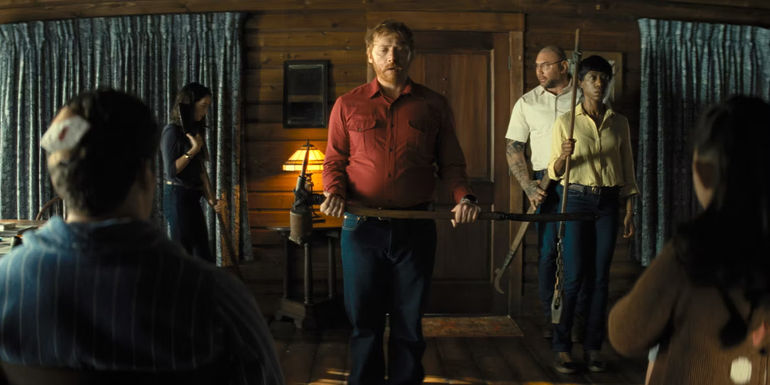 Rupert Grint holding the handle of an old farming tool/ weapon in Knock at the Cabin. - M. Night Shyamalan's Next Movie Continues A Career Trend - What To Expect From Trap