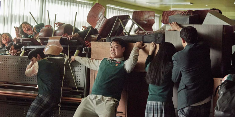 Dae-su and other students holding a barrier in the music room in All of Us Are Dead.