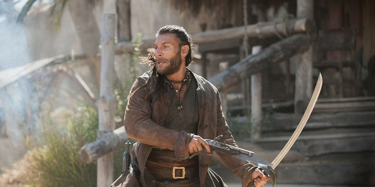 Charles Vane turns around while holding a pistol in one hand and a cutlass in the other in Black Sails.