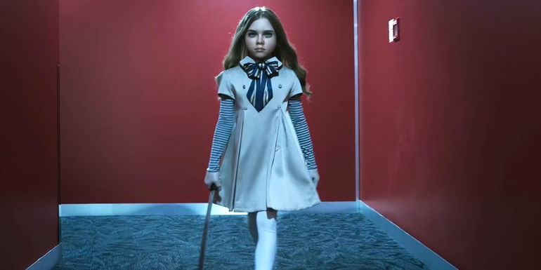 Amie Donald (performer) and Jenna Davies (voice) as M3GAN walking down a red hallway with large knife in hand