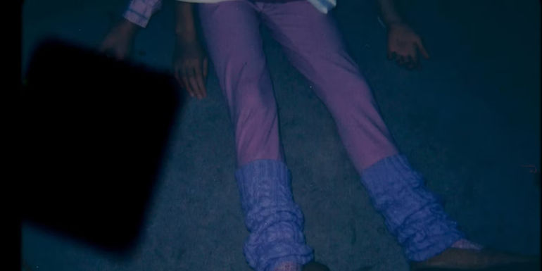 A Half-Viewed Person Lying on a Bed in a Trailer for an Unknown Neon Horror Movie