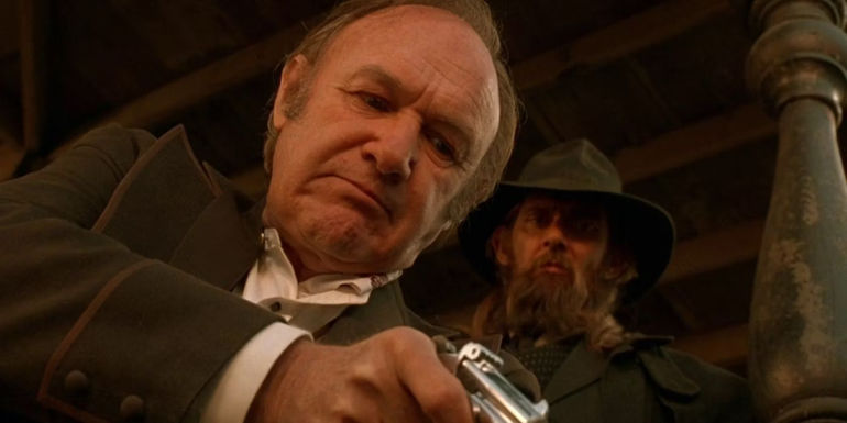 Gene Hackman as John Herod aims a revolver at a civilian's head while his right-hand man watches on in The Quick and the Dead