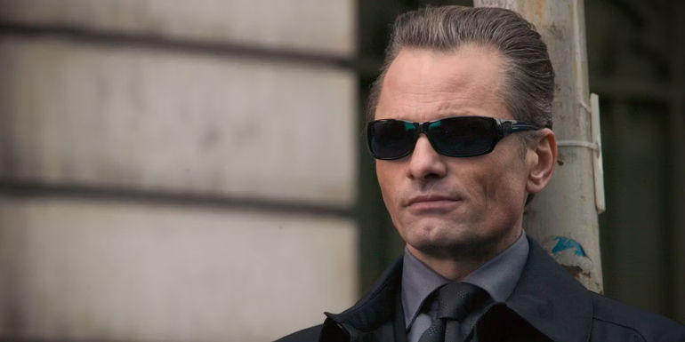 Nikolai Luzhin stoically stands against a scratched up pole while wearing on a pair of dark sunglasses in Eastern Promises