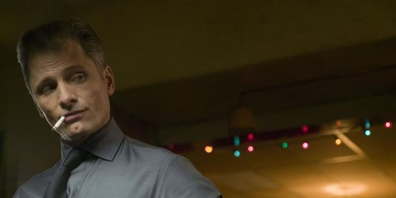 Nikolai Luzhin stands inside a bar with his head tilted to the left with a cigarette in his mouth in Eastern Promises