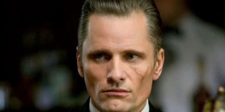 Nikolai Luzhin glares at an off screen foe while exposing his scar inside a bar in Eastern Promises