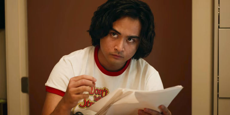 Simon looking up with a stack of papers in his hand in School Spirits