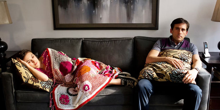 Penny lying on the couch next to Dodge sitting in Seeking a Friend at the End of the World