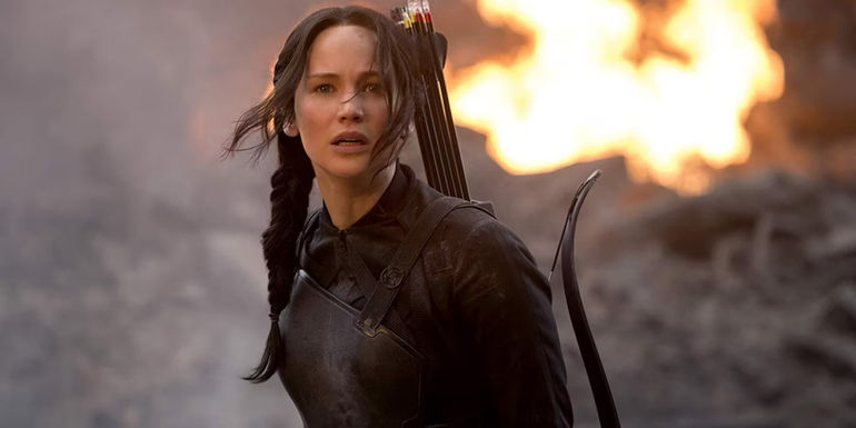 Katniss stands in the street in front of a fire in The Hunger Games Mockingjay Part 1.