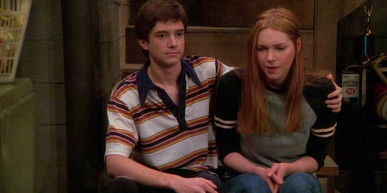 Eric (Topher Grace) with his arm awkwardly around Donna (Laura Prepon) in That '70s Show pilot episode.