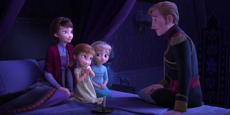 Elsa and Anna atop a bed with their mom and dad sitting in Frozen 2.