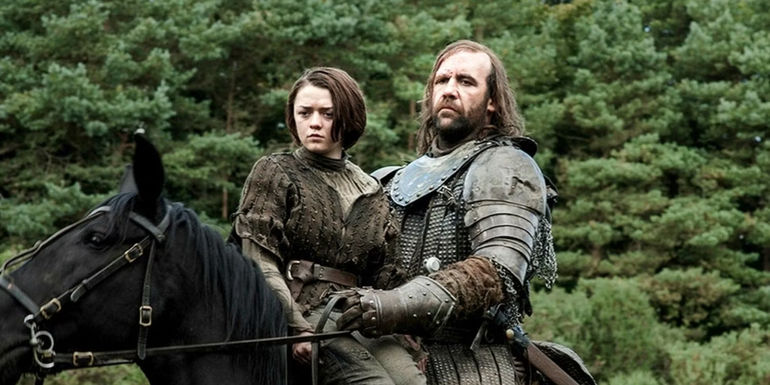 Maisie Williams as Arya Stark riding on a horse with Rory McCann as The Hound in Game of Thrones