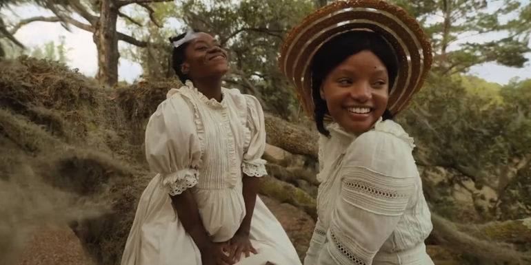 Young Celie and Nettie wearing white dresses and laughing in The Color Purple (2023)