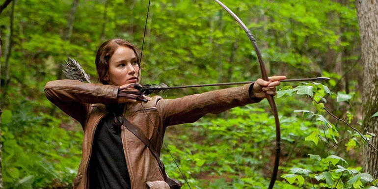 Katniss Everdeen using her bow in the woods in District 12 in The Hunger Games.