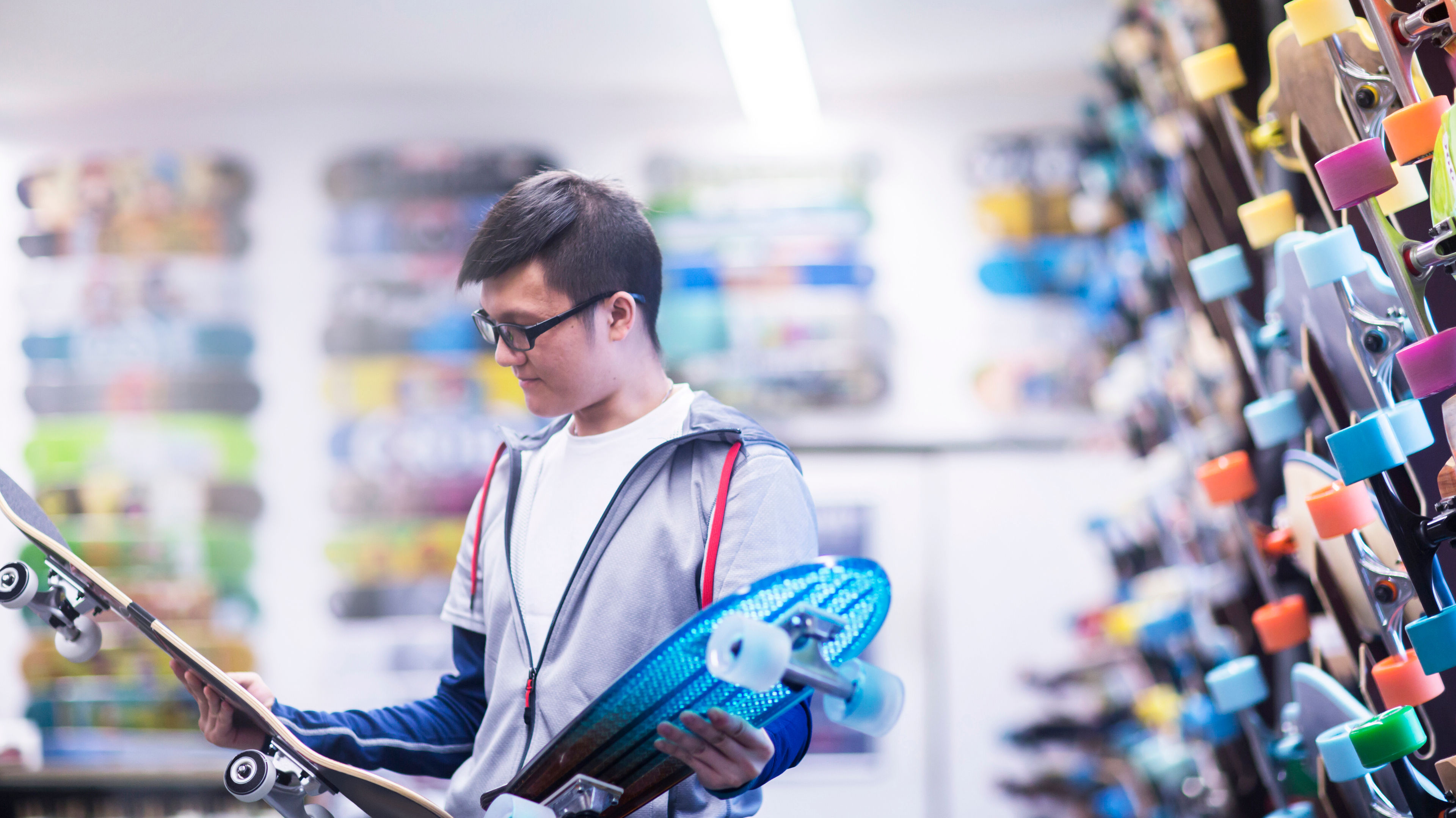 Young male skateboarder looking at skateboards 