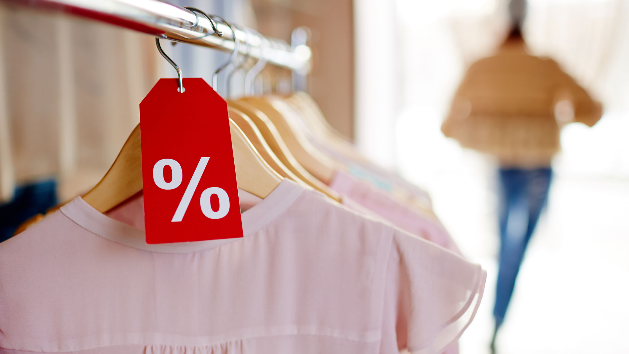 A row of dresses with a % price tag in front 