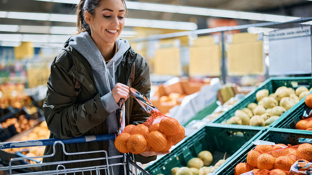 happy-woman-buying-oranges-in-plastic-mesh-at-supe-2022-09-27-22-33-07-utc