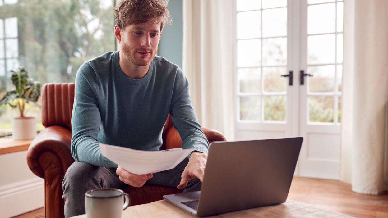 man-sitting-on-armchair-at-home-with-laptop-paying-2022-04-04-21-34-37-utc