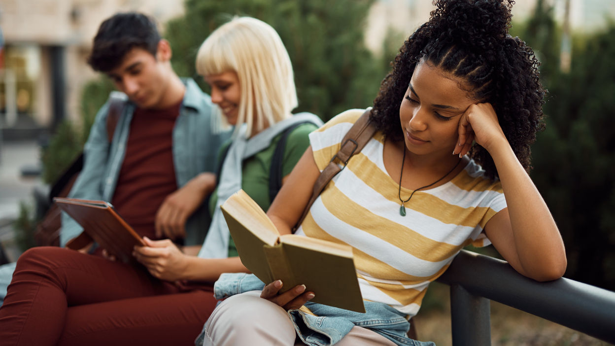 young-black-woman-reading-a-book-at-campus-2022-12-06-01-16-21-utc