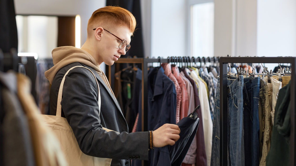 man-looking-at-clothes-while-shopping-sustainably-2022-11-24-18-33-36-utc